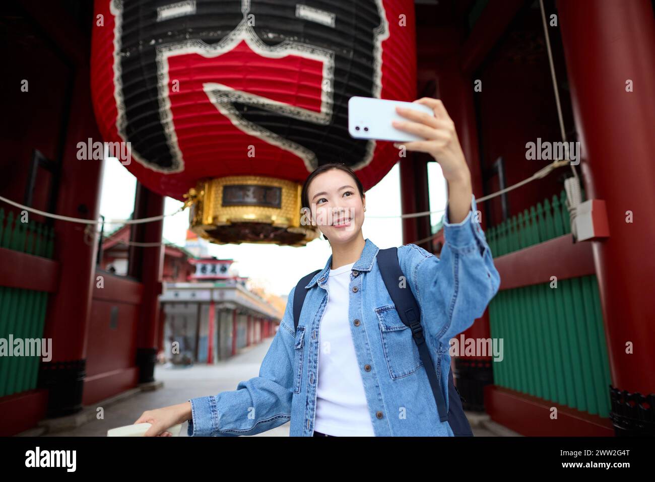 A woman taking a selfie with a camera in front of a red lantern Stock Photo