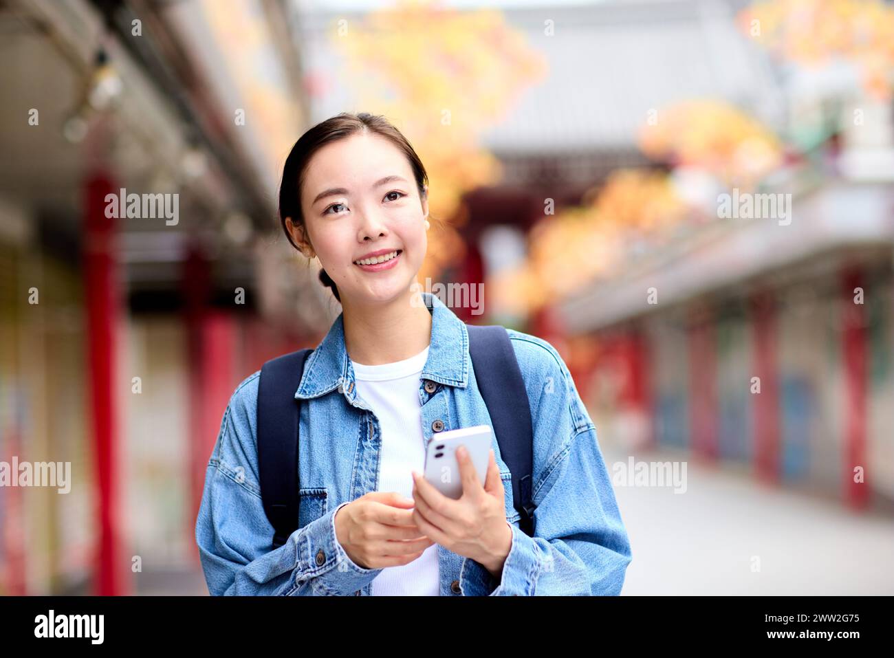 A woman in a denim jacket holding a cell phone Stock Photo