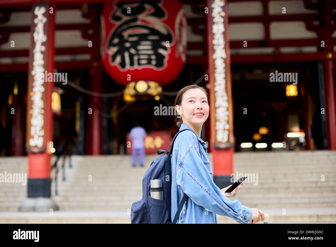 A woman with a backpack standing in front of a temple Stock Photo
