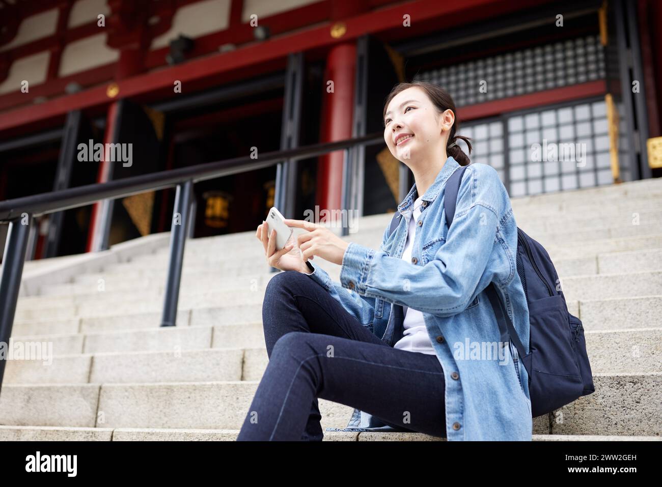 Asian woman sitting on steps with her phone Stock Photo