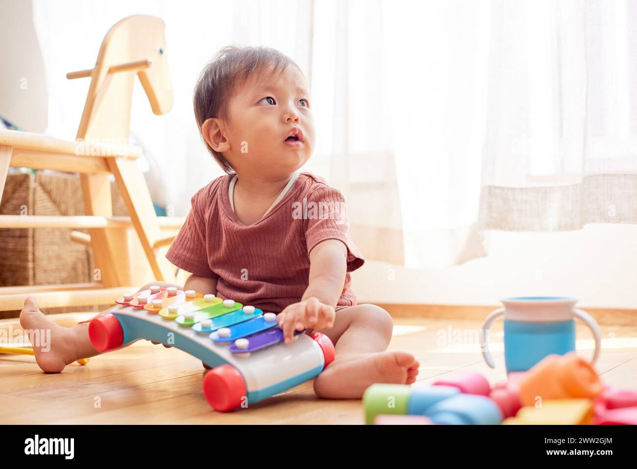 A baby playing with toys on the floor Stock Photo
