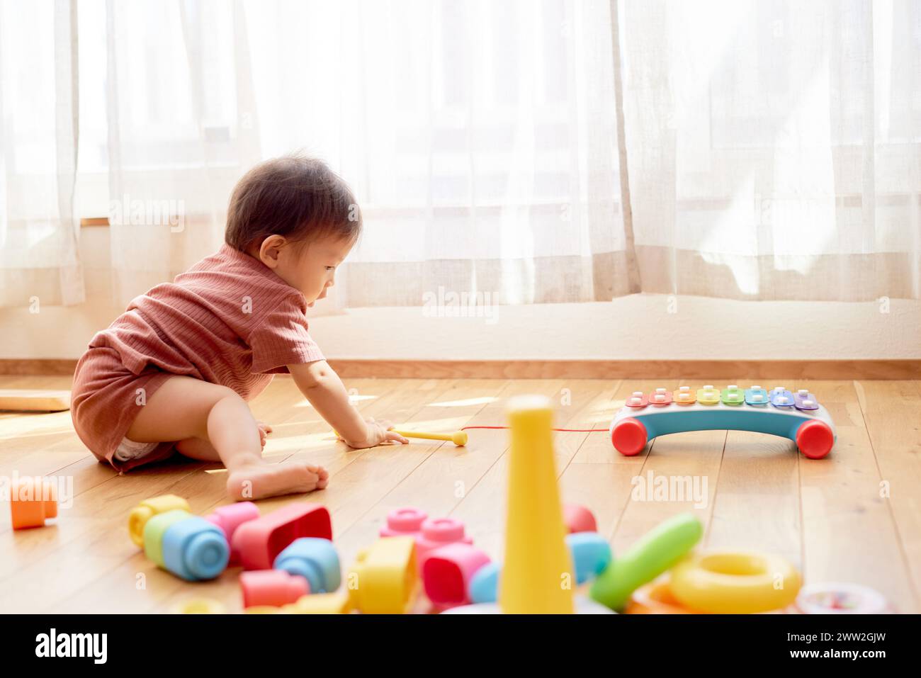 A baby playing with toys on the floor Stock Photo