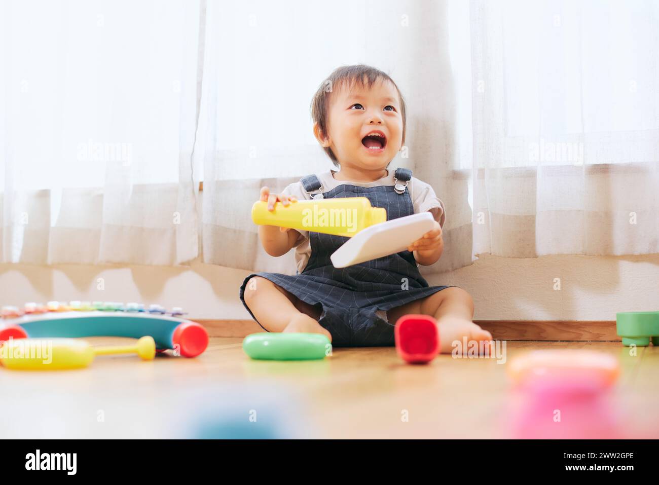 A baby playing with toys on the floor Stock Photo