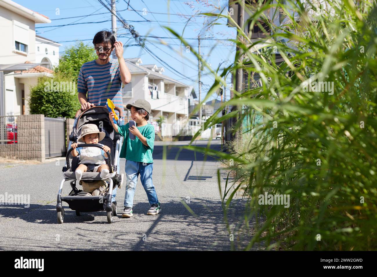 A man and two children walking down a street Stock Photo