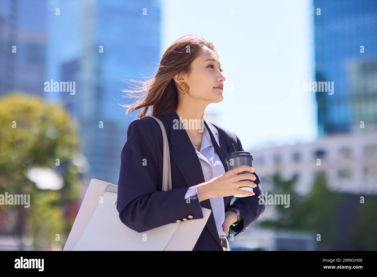 Asian business woman with coffee and bag in city Stock Photo