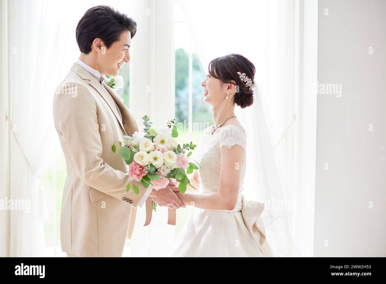 A bride and groom standing in front of a window Stock Photo - Alamy