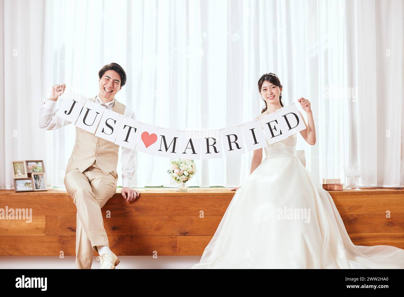 A newly married couple holding a banner that says just married Stock Photo