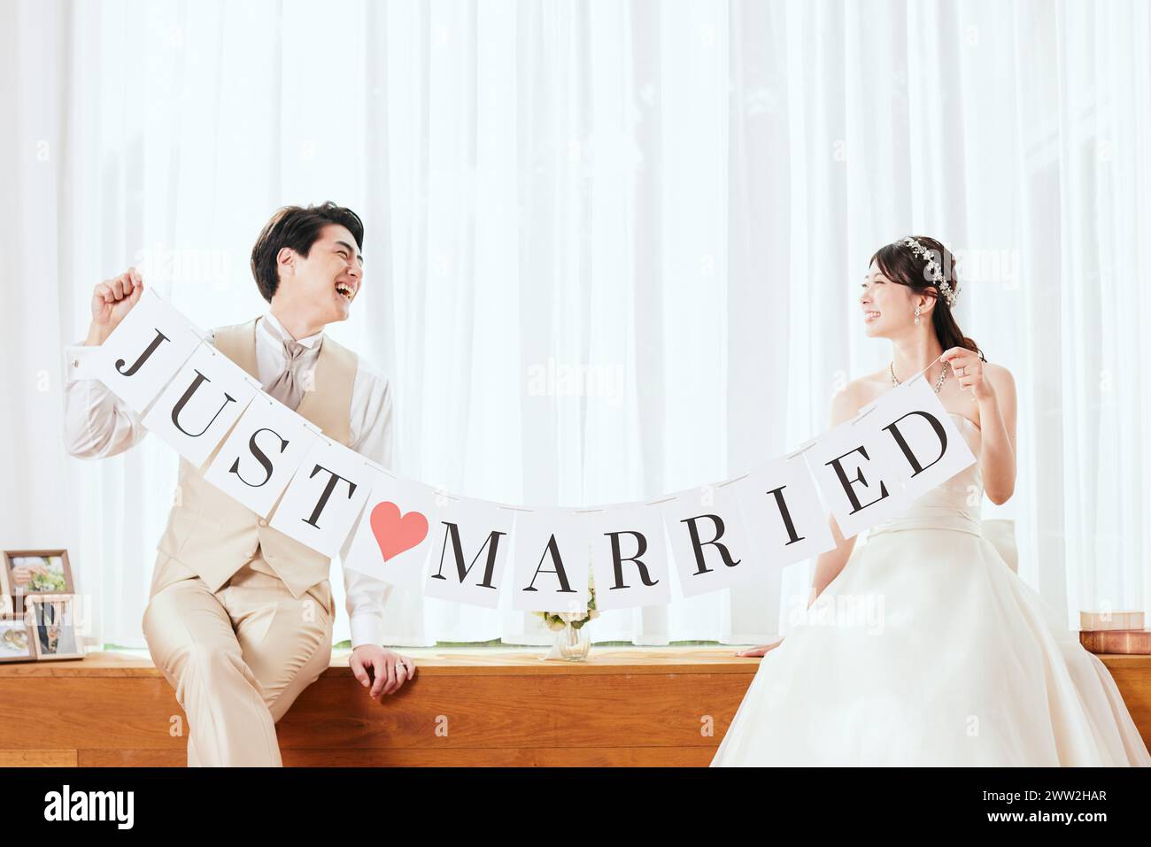 A bride and groom holding up a banner that says just married Stock Photo