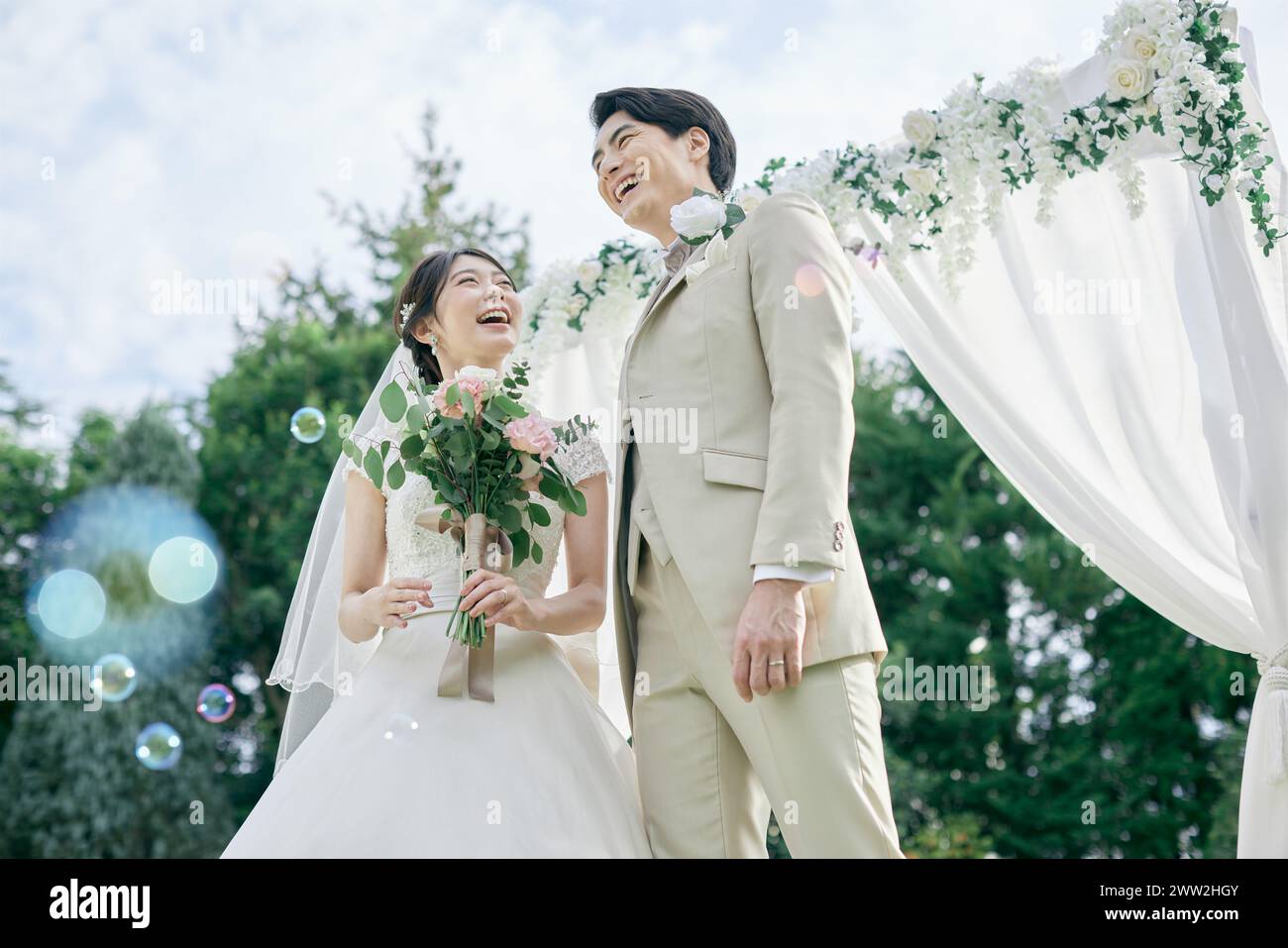 A newly married couple standing under a wedding arch Stock Photo