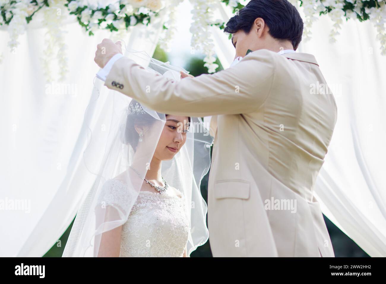 Groom lifting bride veil at wedding Stock Photo