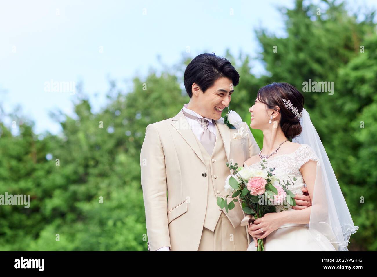 A newly married couple standing in the grass Stock Photo