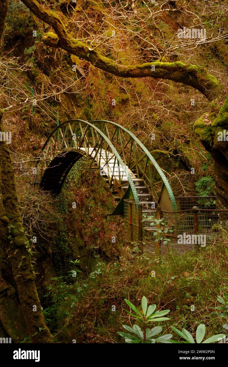 Arched metal pedestrian bridge over the river Afon Mynach in Wales.UK ...