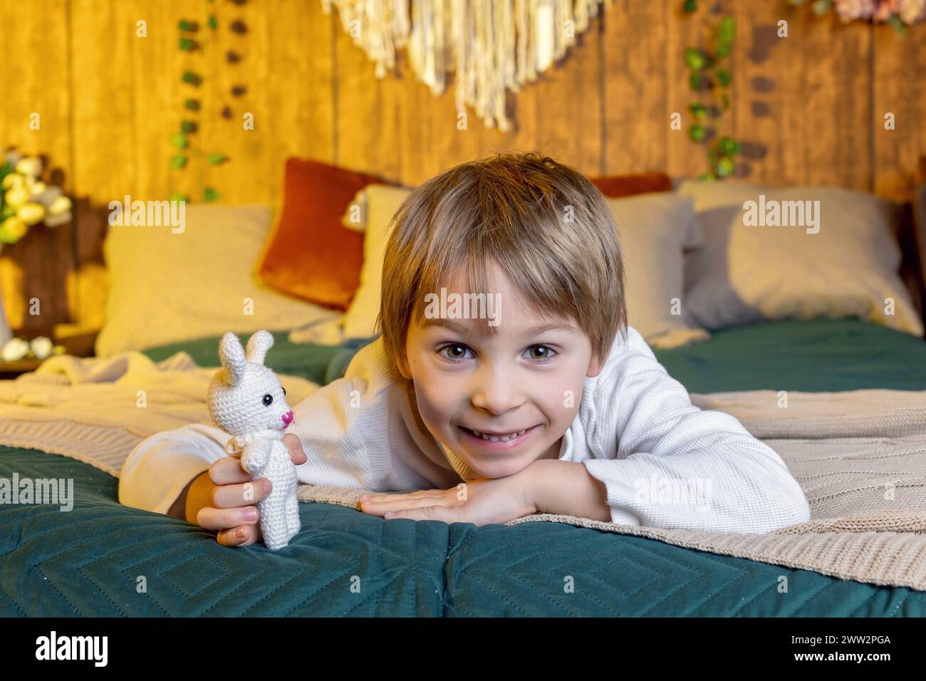 Cute school child, boy, holding basket with easter eggs on easter background, studio shot Stock Photo