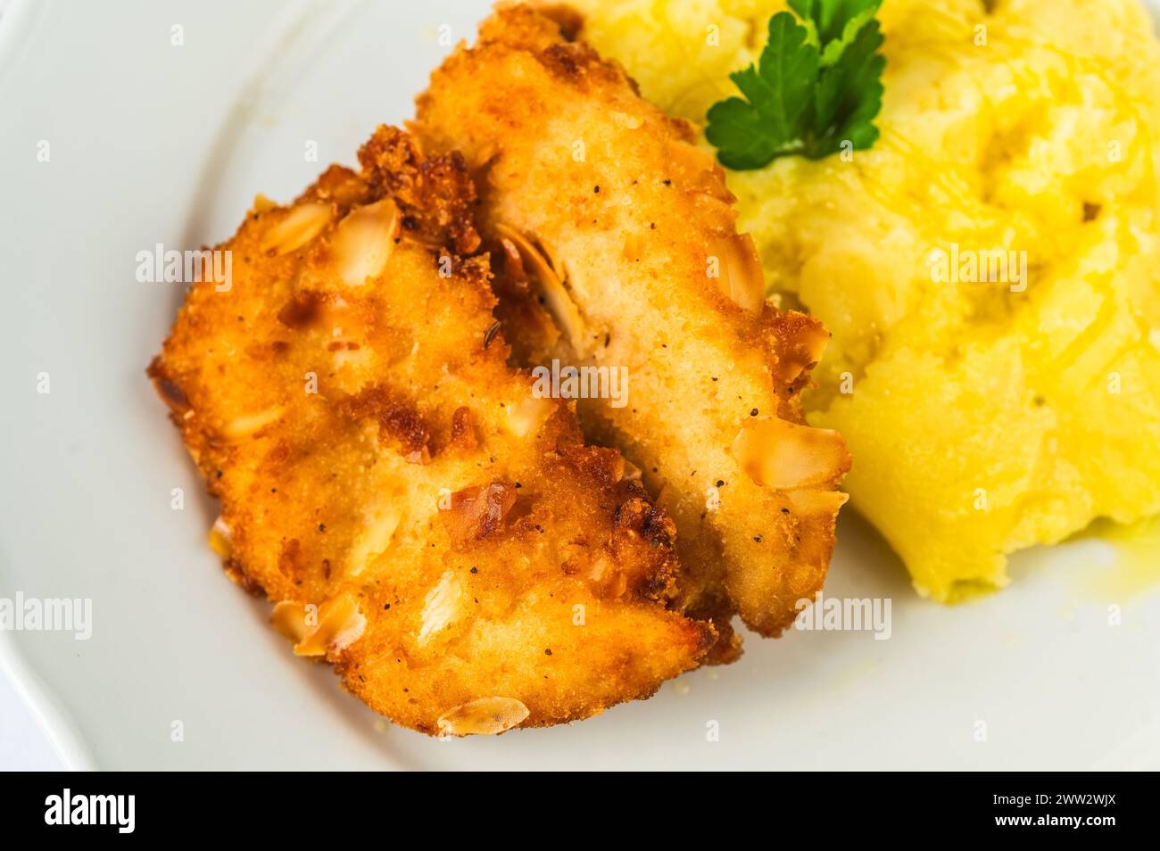 Fried schnitzel in breadcrumb and almond, mashed potato on white plate, closeup. Stock Photo