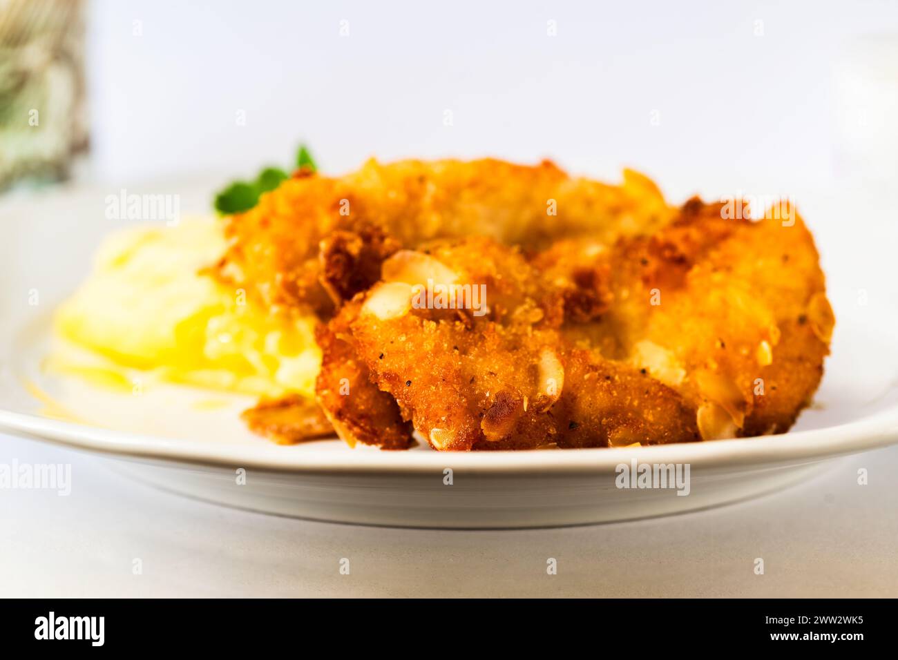 Fried schnitzel in breadcrumb with almonds, mashed potato on white plate, closeup. Stock Photo