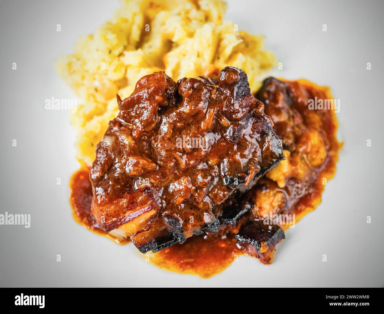 Baked juicy pork rib piece in spicy red sauce with mashed potato, closeup. Stock Photo