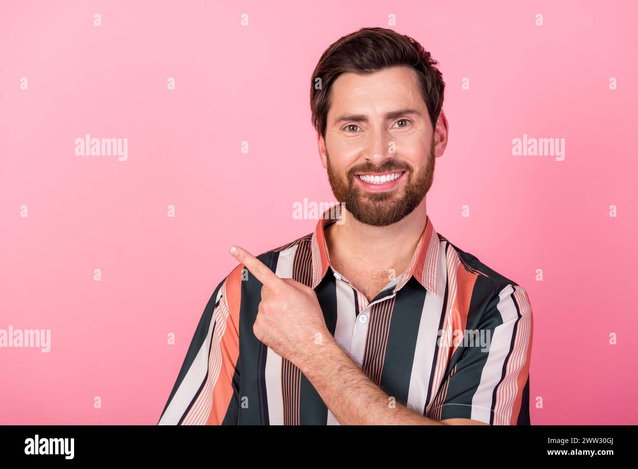 Portrait of positive young man beaming smile direct finger empty space ...