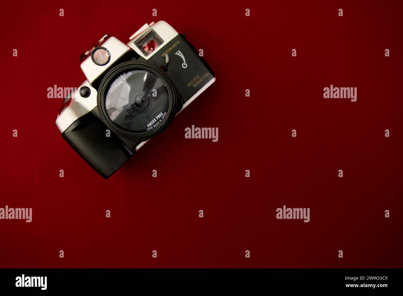 A high-resolution image featuring a vintage camera positioned flat against a solid red surface Stock Photo