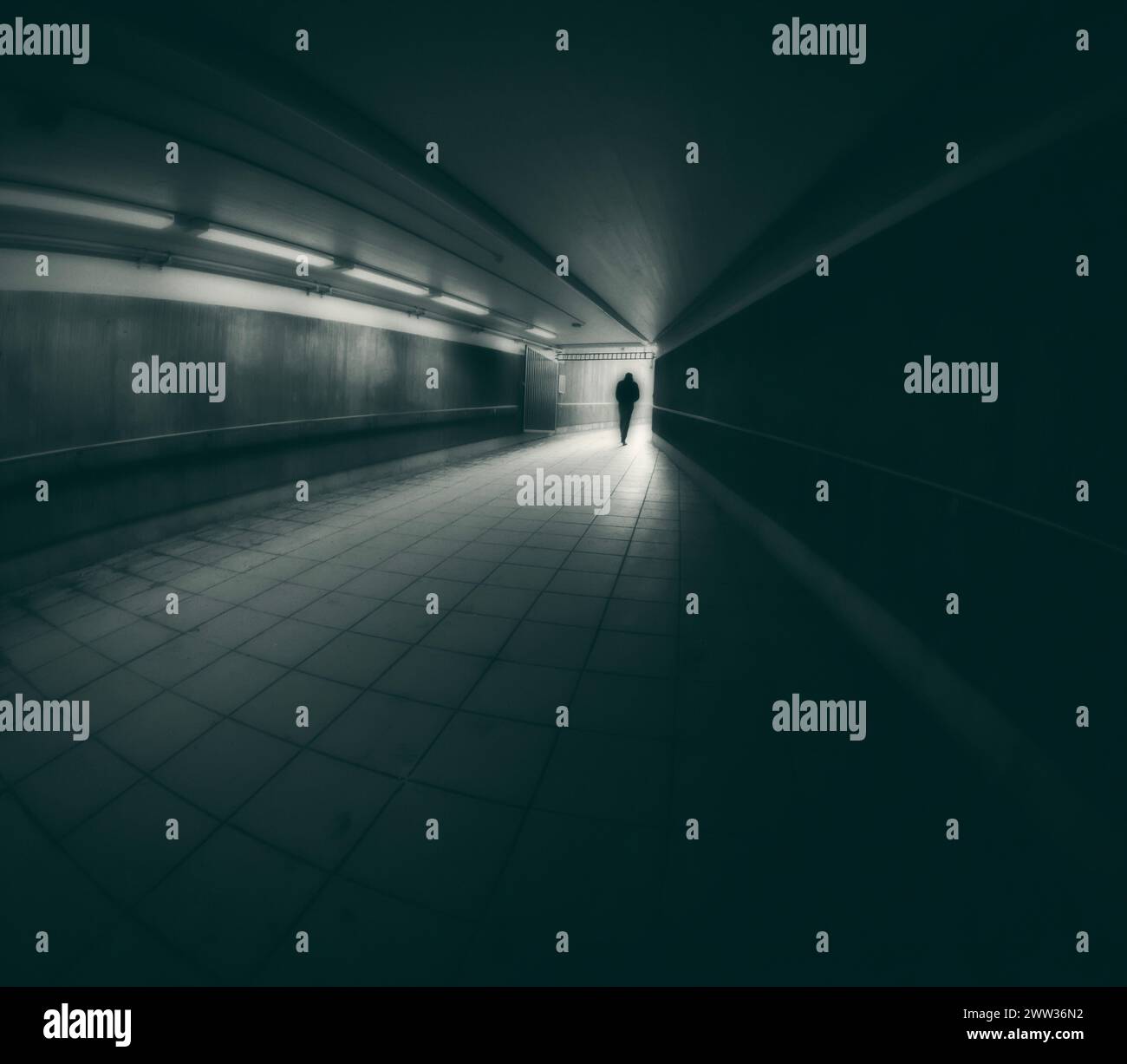 Creative dreamlike image of lonely young person walking toward the light in a tunnel. Stock Photo