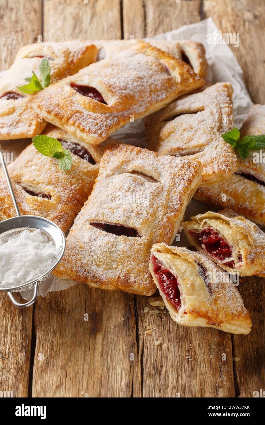Cherry puff pastry with powdered sugar and mint close-up on the table. Vertical Stock Photo