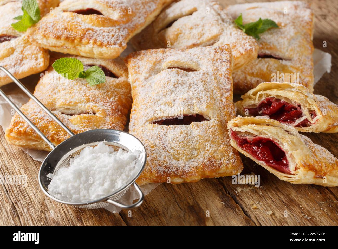 Sweet berry puff pastry with powdered sugar and mint close-up on the table. Horizontal Stock Photo