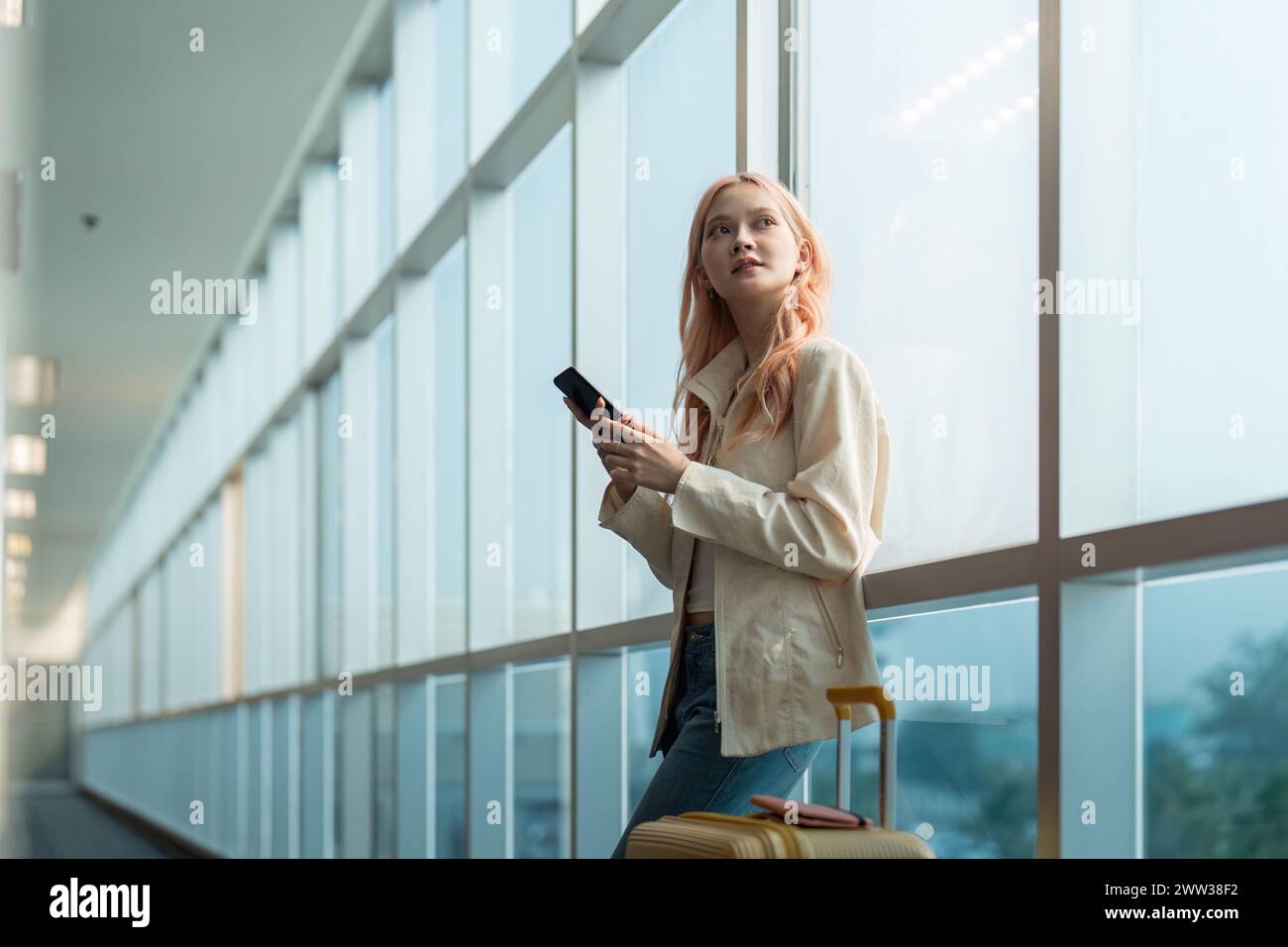 Traveler woman asian in airport and luggage for vacation, smile and holding the phone check boarding ticket. Female traveler with suitcase Stock Photo