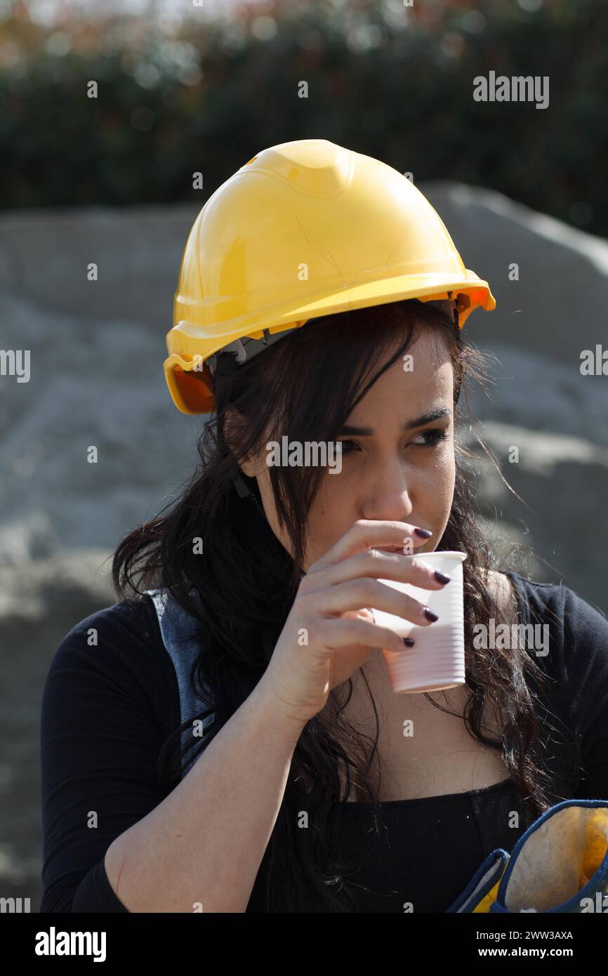 A construction worker in a yellow helmet is taking a break Stock Photo