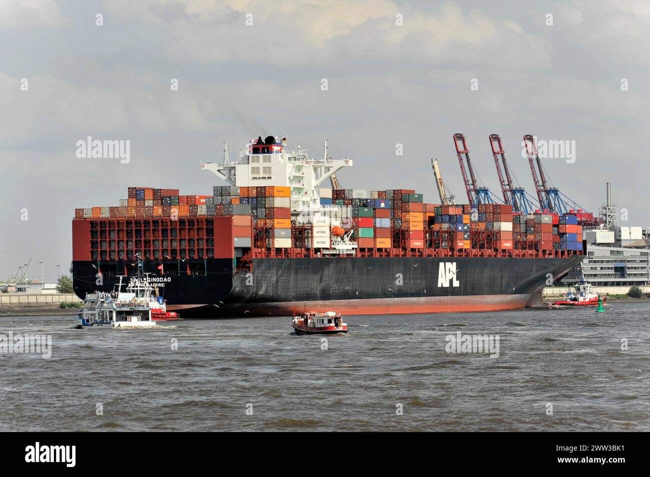 Container ship is docked in the harbour, surrounded by tugboats and cranes, Hamburg, Hanseatic city, Germany Stock Photo