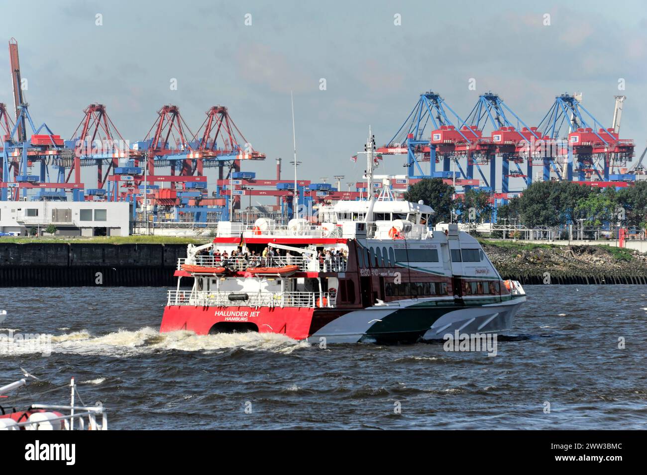 A passenger ship passes container cranes in Hamburg harbour, Hamburg, Hanseatic City of Hamburg, Germany Stock Photo