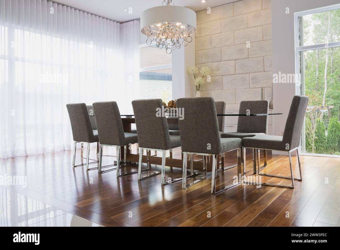 Glass dining table with gray upholstered high back chairs in dining room inside luxurious home, Quebec, Canada Stock Photo