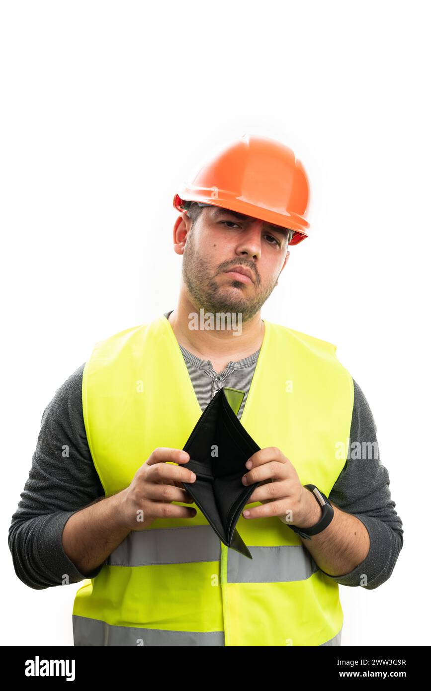 Sad constructor man wearing fluorescent vest and safety helmet presenting empty leather wallet as poor cashless concept isolated on white studio backg Stock Photo