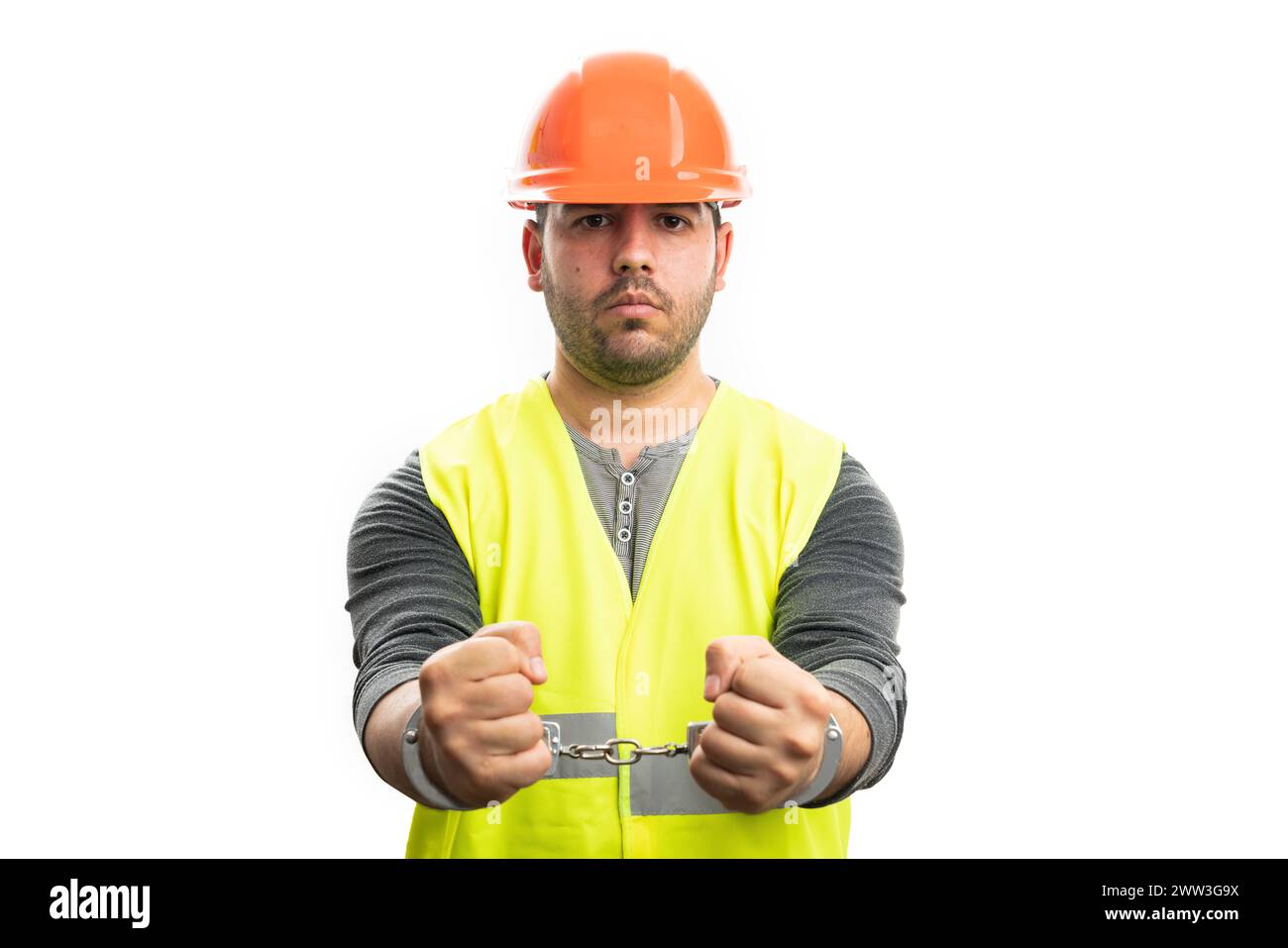 Corrupted adult male constructor in handcuffs wearing safety hardhat and fluorescent vest as work attire isolated on white studio background Stock Photo