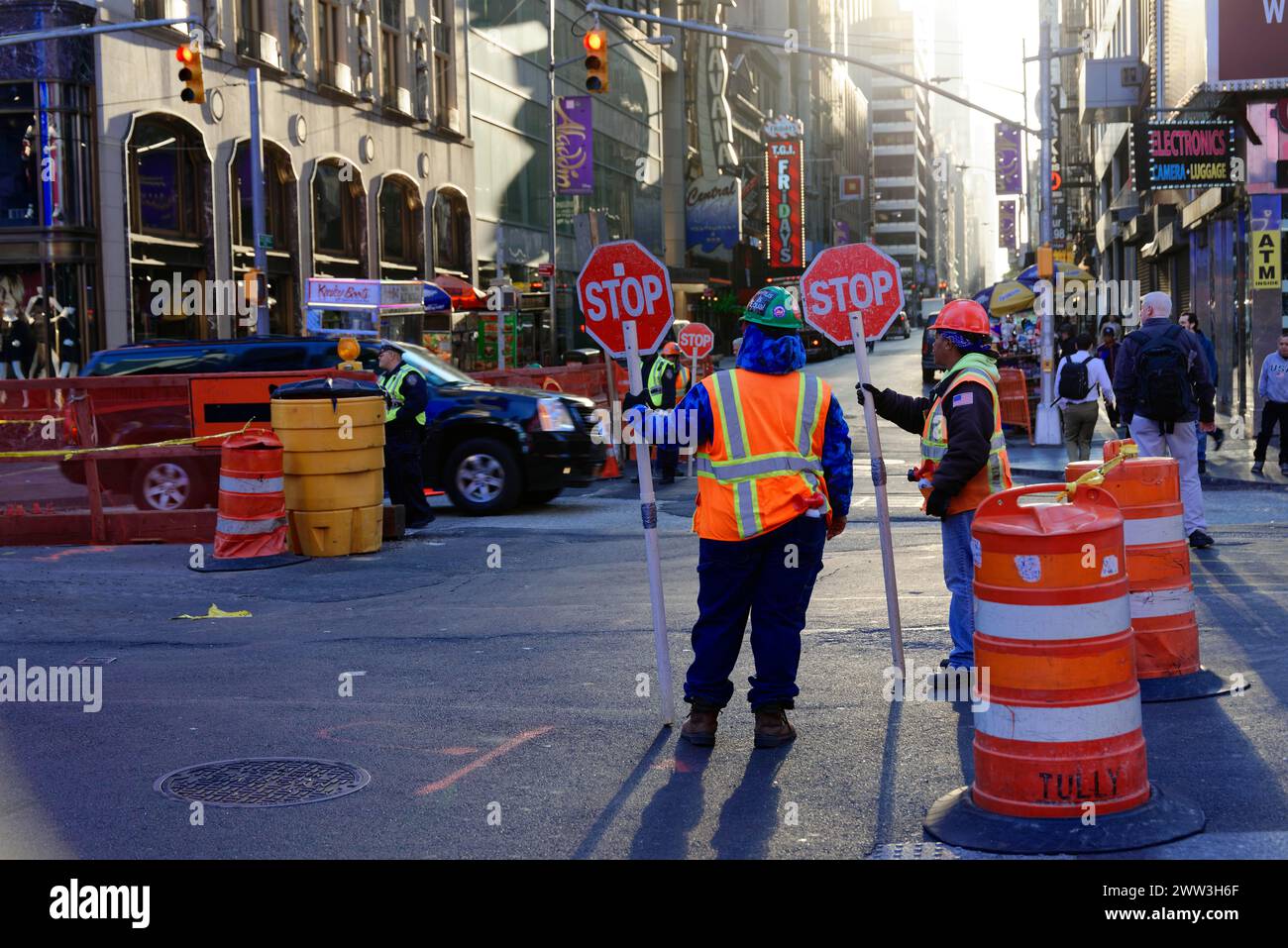 Several road workers holding STOP signs during construction work on a busy city street, Manhattan, New York City, New York, USA, North America Stock Photo