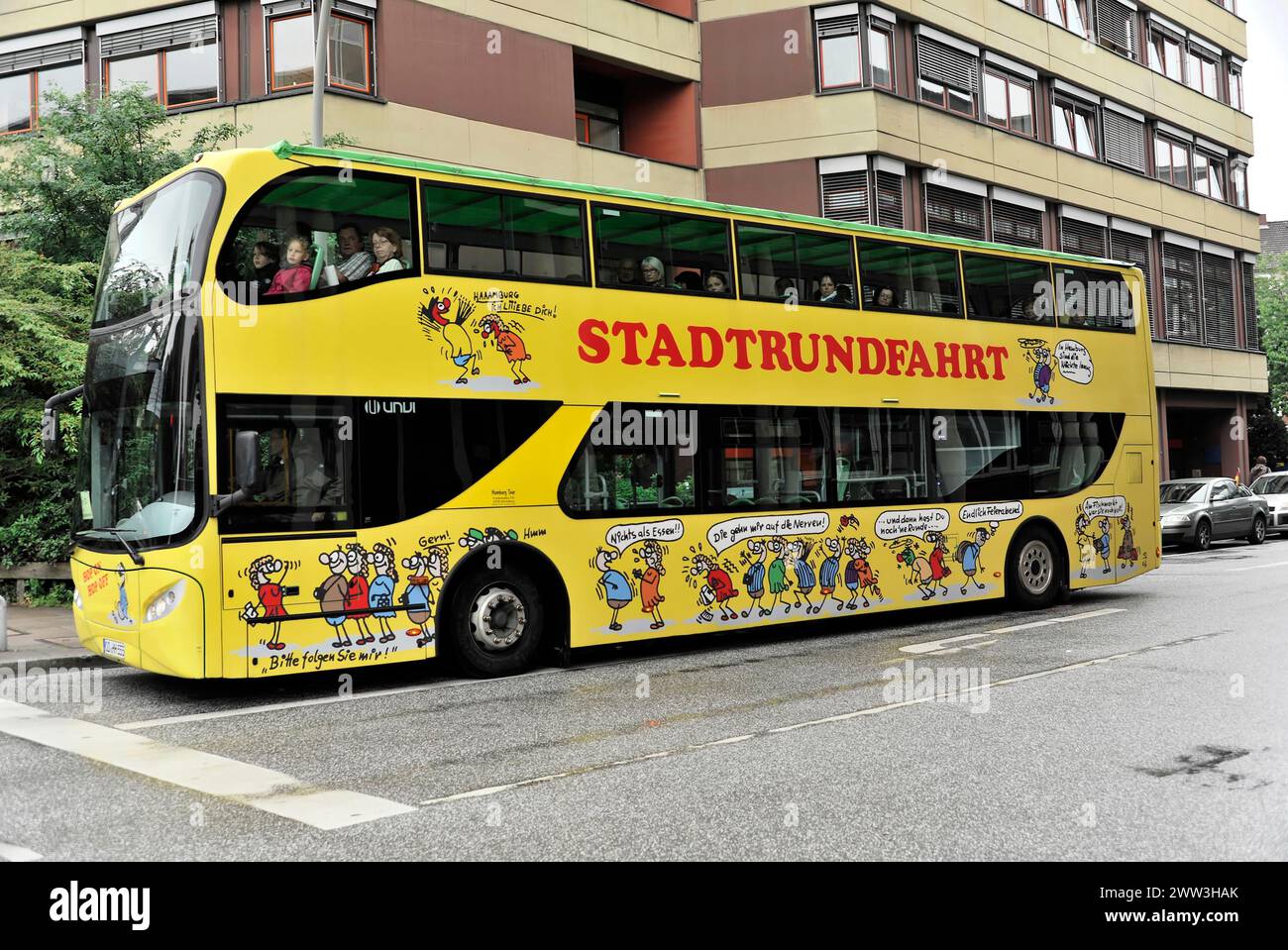 A yellow doubledecker sightseeing bus with cartoon character motifs