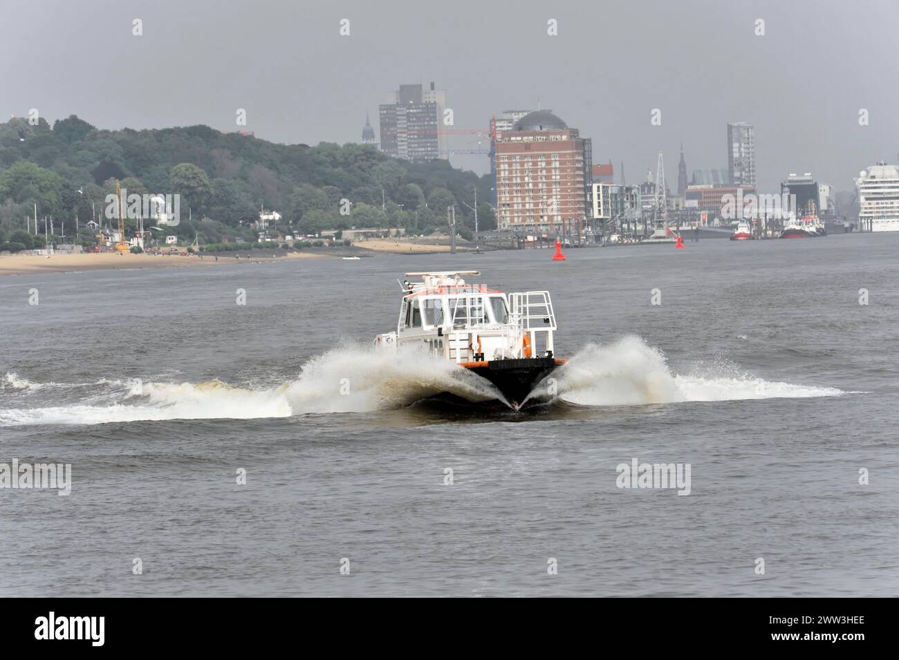 A speedboat cruises quickly through the harbour water and leaves waves in its wake, Hamburg, Hanseatic City of Hamburg, Germany Stock Photo