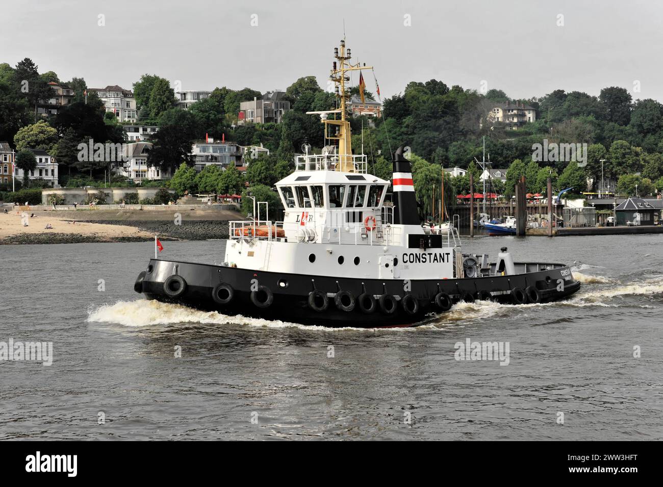 A tugboat sailing on a river (Elbe) with a city in the background, Hamburg, Hanseatic City of Hamburg, Germany Stock Photo
