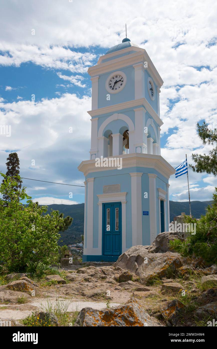A blue and white clock tower under a sunny sky with the Greek flag and surrounding nature, Poros, Poros Island, Saronic Islands, Peloponnese, Greece Stock Photo