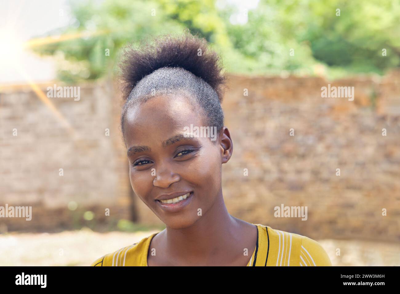 single young african woman with a big smile standing in the backyard Stock Photo