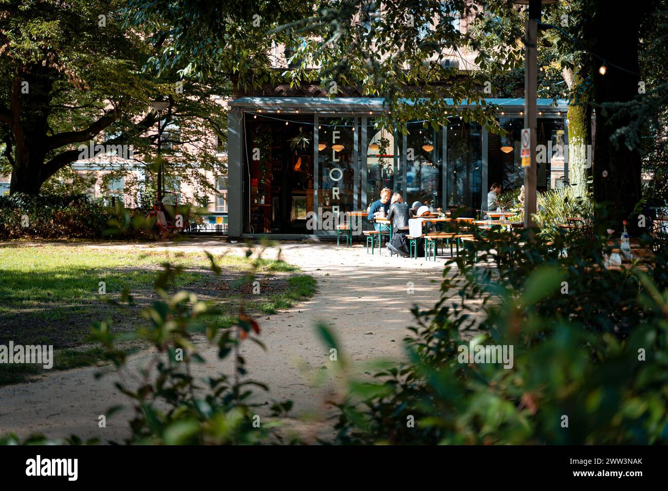 A cozy café nestled among trees in a serene park setting with patrons enjoying outdoors Stock Photo