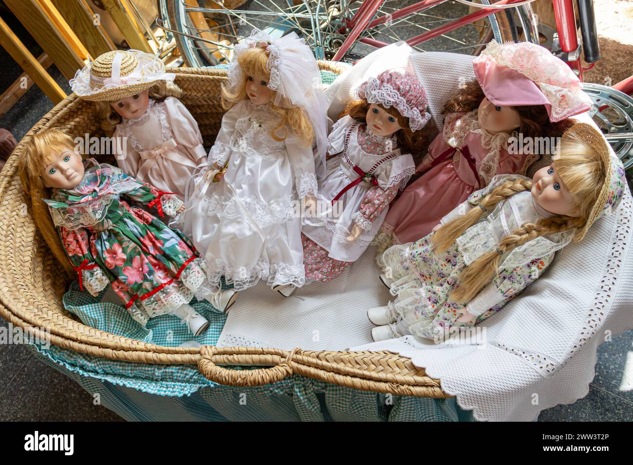 antique porcelain dolls in blue wicker cradle, in the shop window Stock Photo