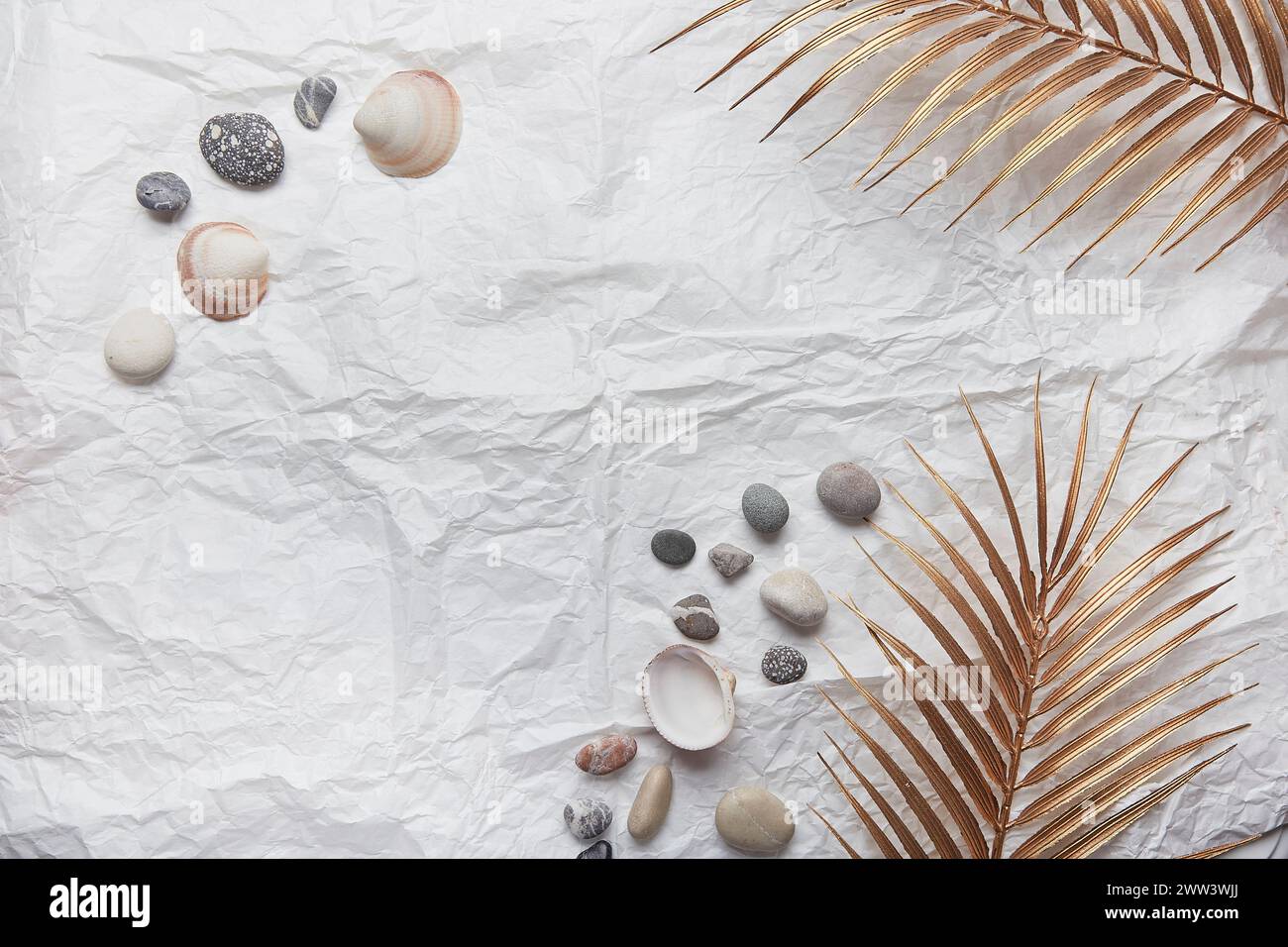 Elegant summer background with golden palm, seashells, pebbles and copy space. Stock Photo