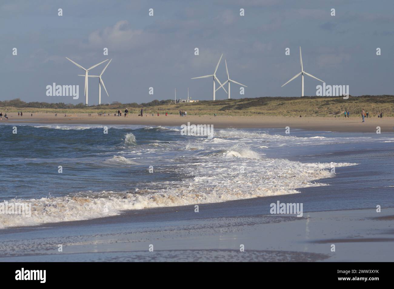 several wind turbines, with beach and the sea in the foreground Stock Photo
