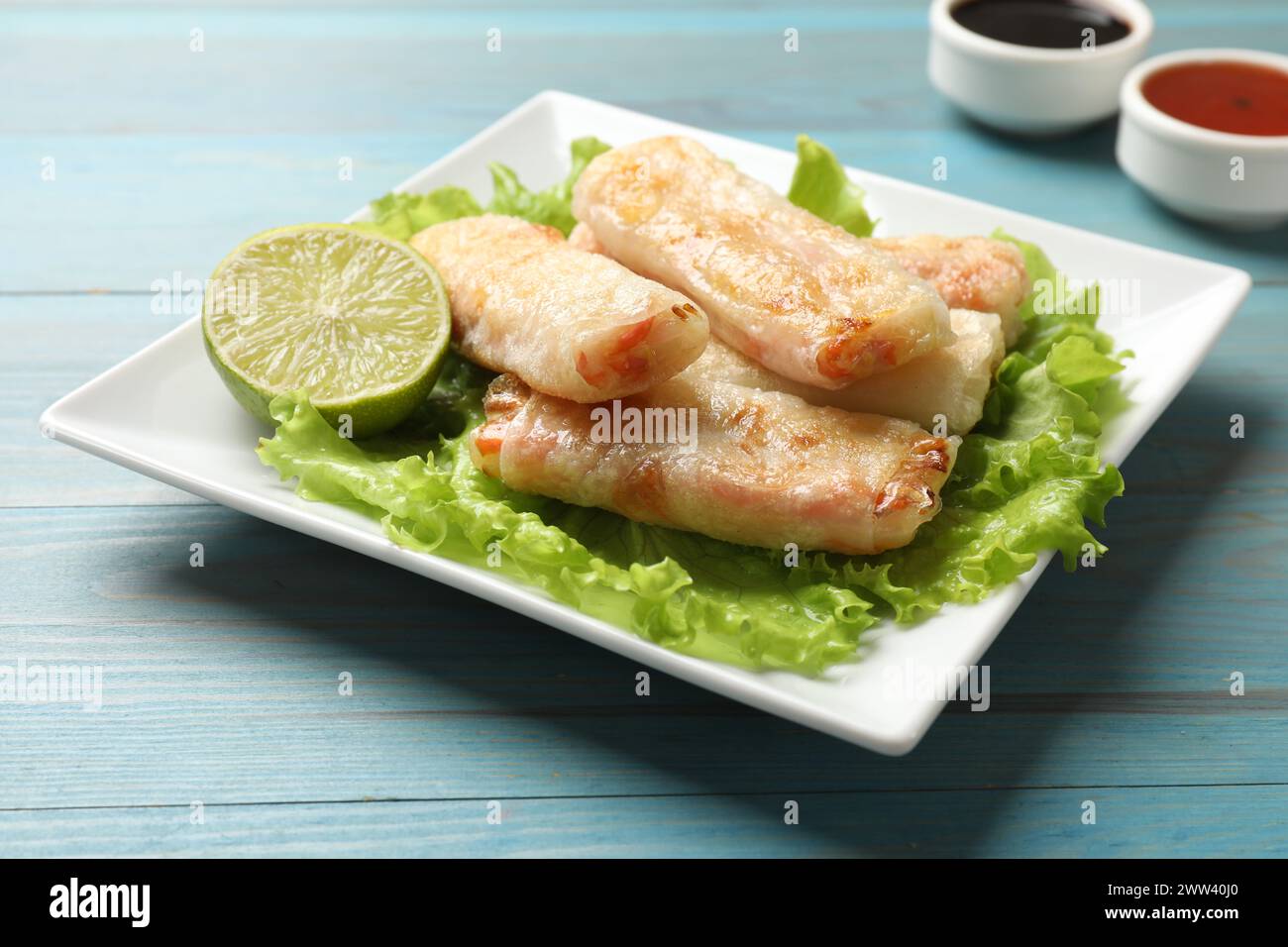Delicious fried spring rolls on light blue wooden table Stock Photo