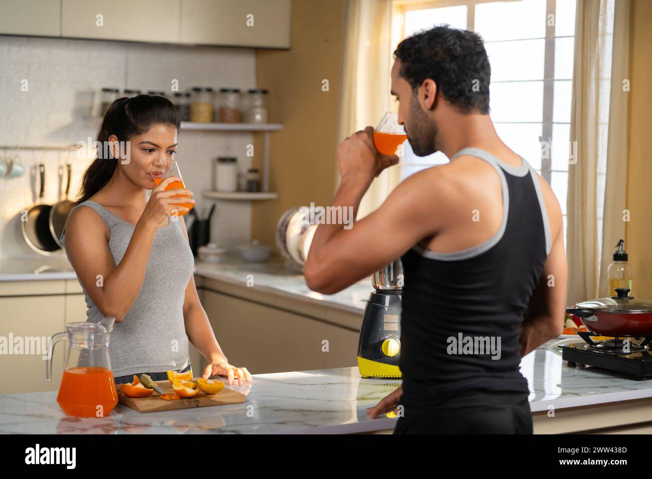 Joyful active fitness couples drinking nutritious orange juice after