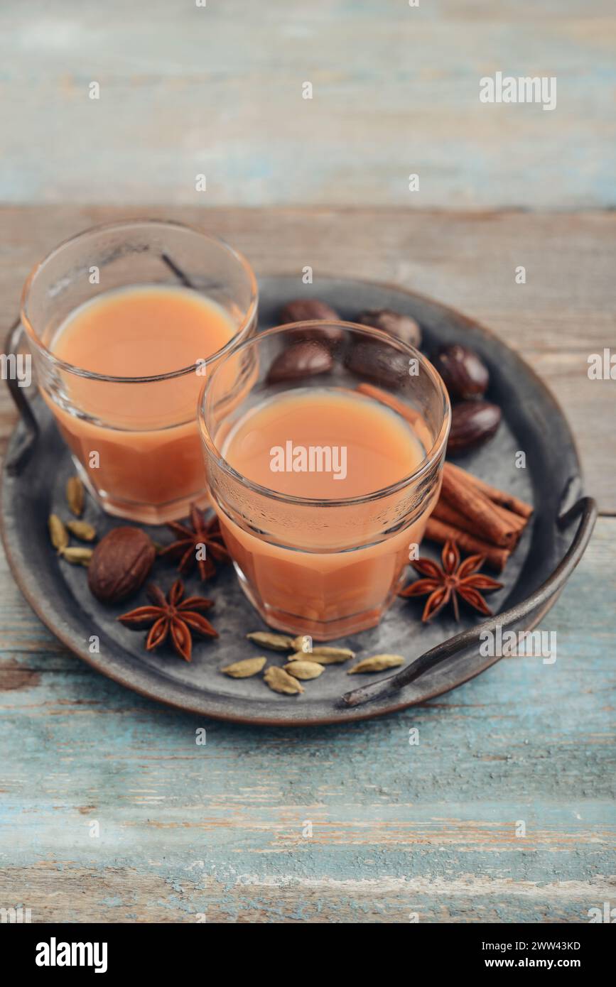 Traditional indian drink - masala tea with spices on metal tray on wooden background Stock Photo