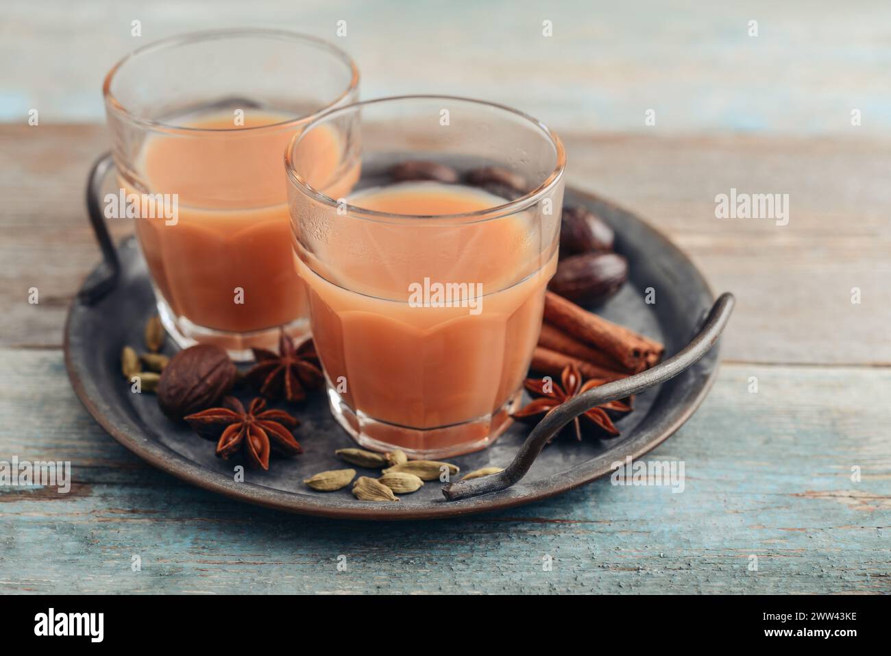 Traditional indian drink - masala tea with spices on metal tray on wooden background Stock Photo