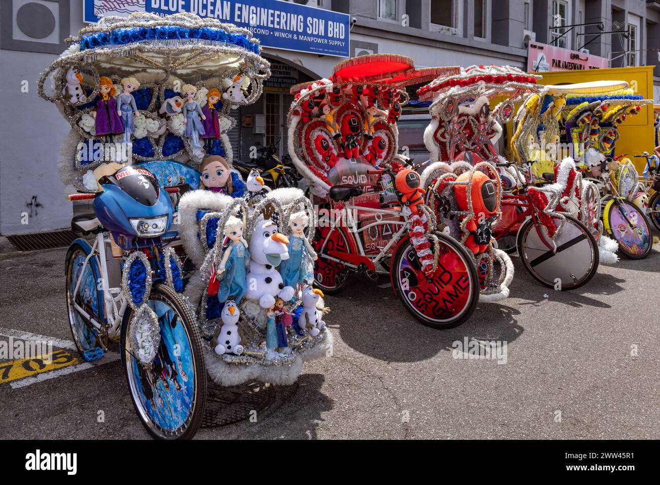 Trishaws, or cycle rikshaws, decorated with popular film and cartoon characters and waiting to transport tourists in Malacca, Malaysia Stock Photo