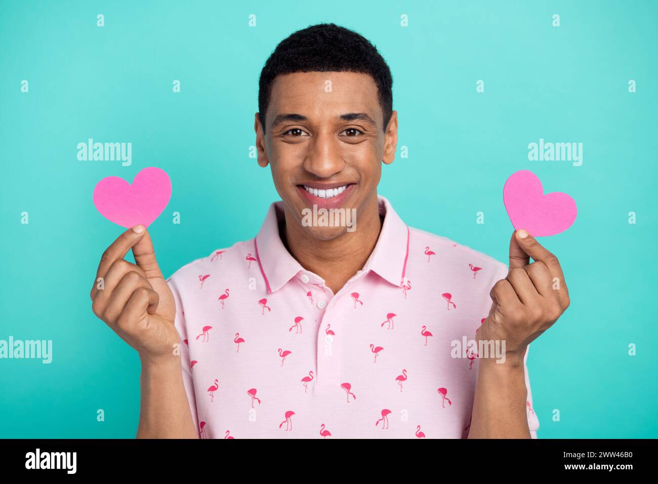 Photo of attractive cheerful man beaming smile hands hold small heart symbol cards isolated on teal color background Stock Photo