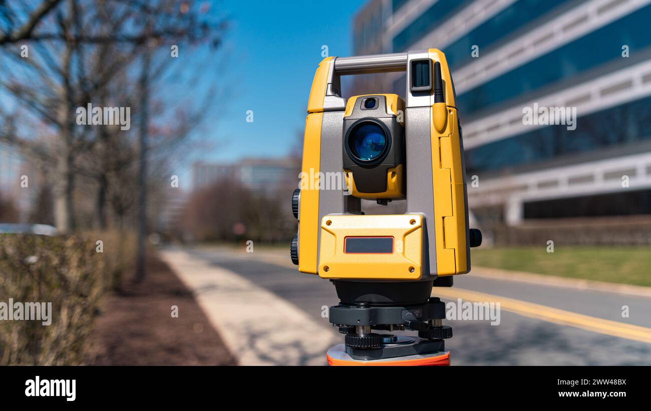 land surveying total station instrument on a tripod with a building in the background Stock Photo