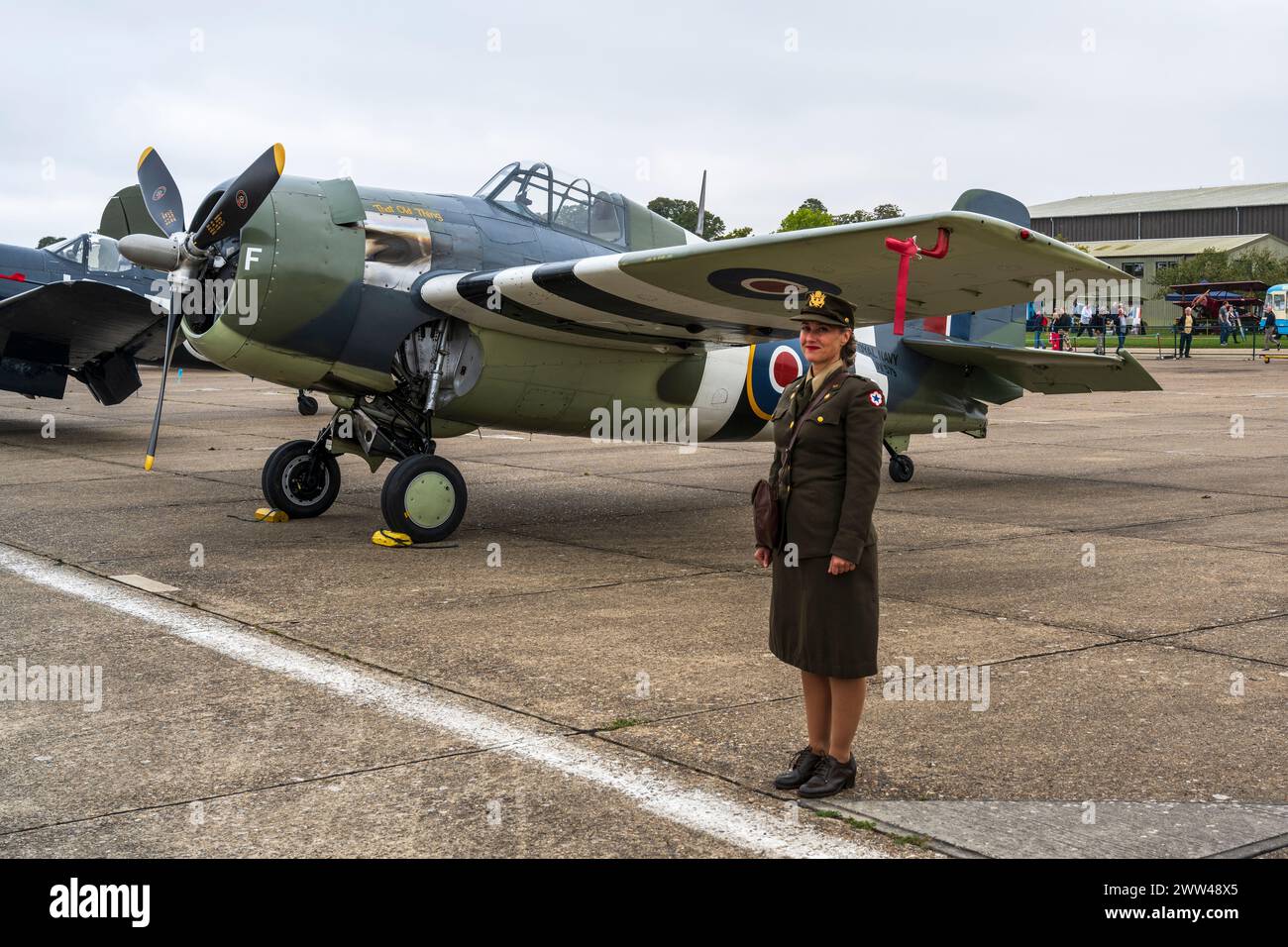 Woman in WAF uniform stands next to a Grumman FM2 Wildcat at Duxford Battle of Britain Air Show 2022, Duxford Airfield, Cambridgeshire, England, UK Stock Photo